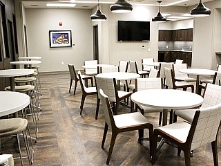 work lunch, break room area. White round tables both tall and standard height tables with white fabric chairs.